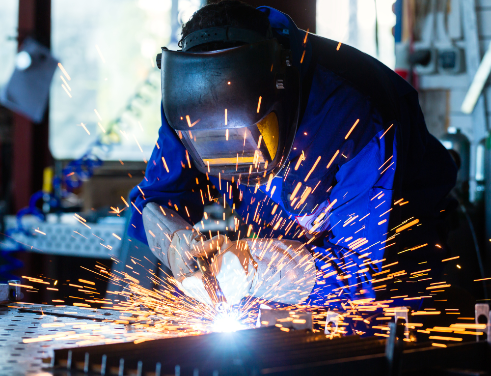 Profissional trabalhando na fabricação de bancos e estruturas metálicas na fábrica da Astra Bancos.
